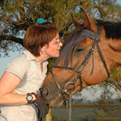 A woman smiling at a horse.