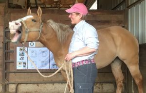 Photo of Becky Tenges with a horse who is yawning.