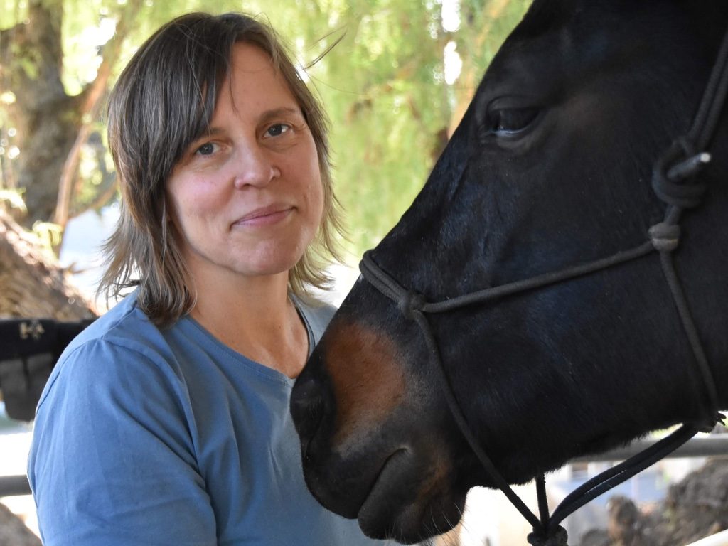 A woman smiling with a horse.