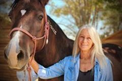 A woman smiling with a horse.