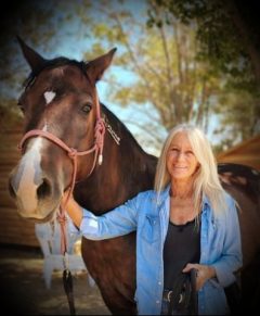 A woman smiling with a horse.