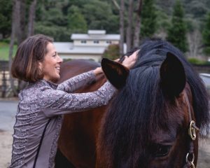 Photo of Jec with hands on horse's back