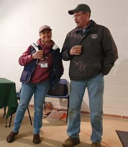 Photo of Vicky and Jim standing together with a cup, smiling.