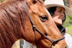 A woman smiling with a horse.