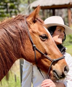 A woman smiling with a horse.