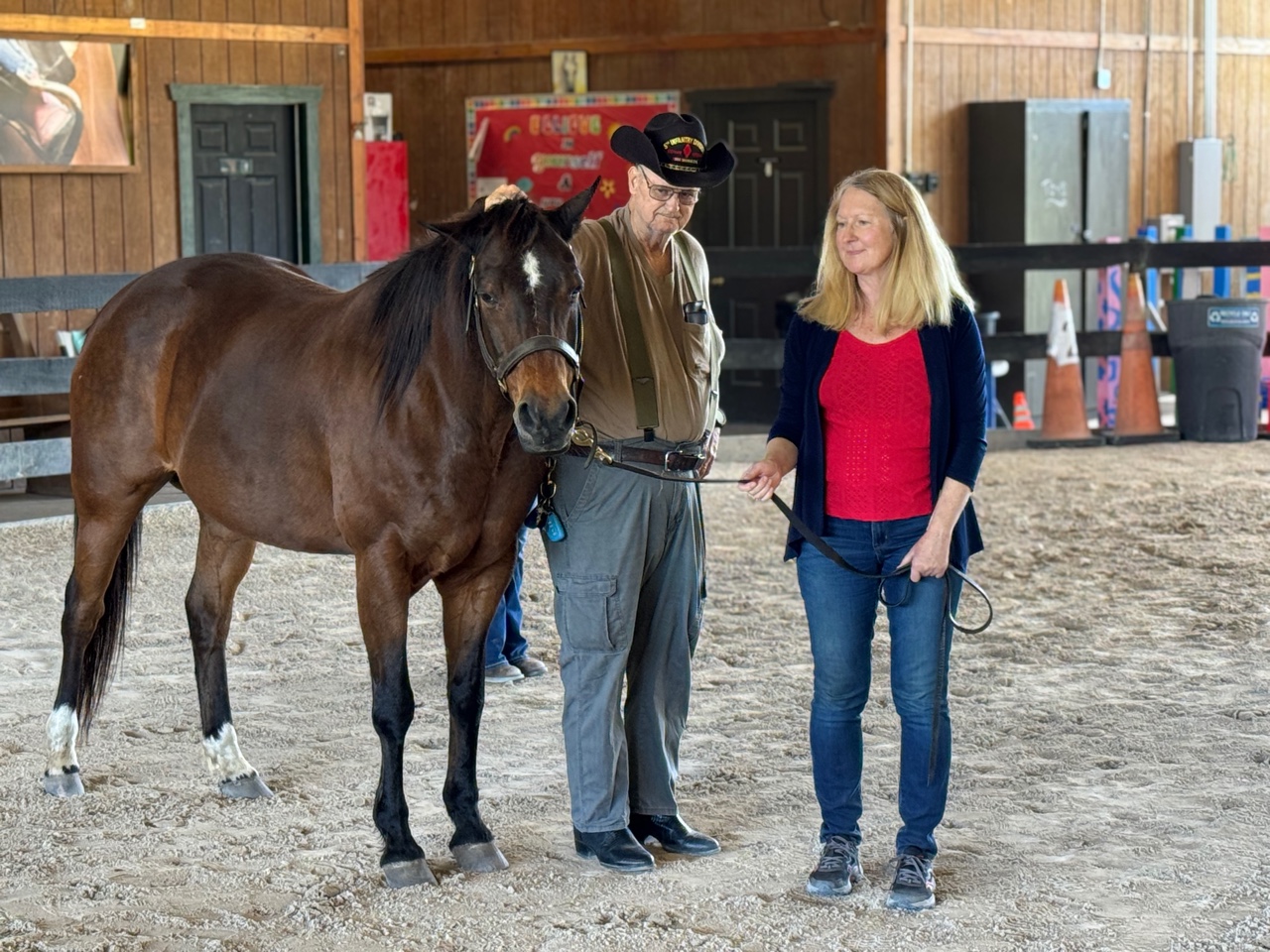 Photo of man resting his hand on horse's poll and woman holding lead rope.