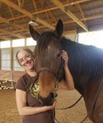 A woman smiling with her horse.