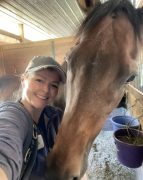 A woman smiling with her horse.