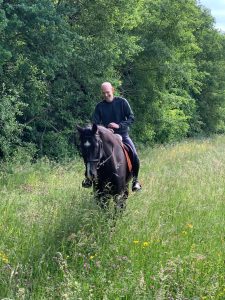 A man riding a horse through a pasture.