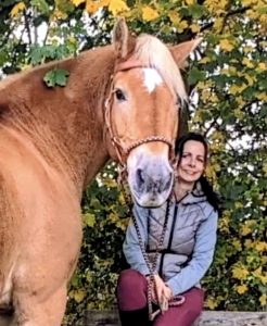 A woman sitting with a horse.