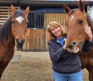A woman laughing with 2 horses.