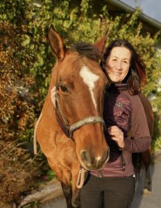 A woman smiling with a horse.