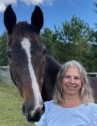 A woman smiling with a horse.