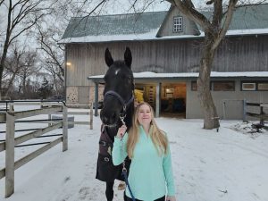 A woman standing with her horse.
