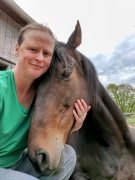 A woman smiling with her horse.