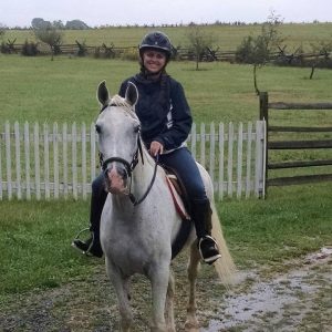 A woman riding a white horse.