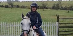 A woman riding a white horse.