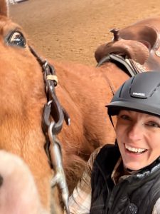 A woman laughing with her horse.