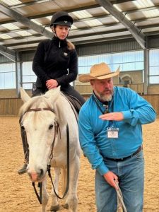 Photo of man giving instruction next to horse and rider