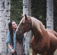 A woman smiling at her horse.