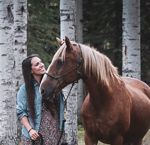 A woman smiling at her horse.