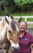A woman, smiling, with her horse.
