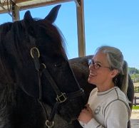 A woman smiling at her horse.