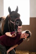 A woman laughing with her horse.
