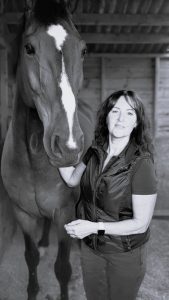 A woman standing with her horse.