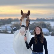 A woman, smiling, with her horse.