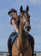 A woman riding a horse, smiling.