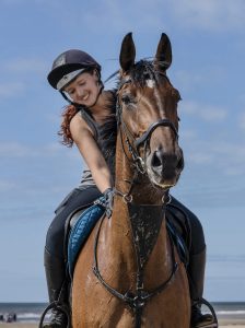 A woman riding a horse, smiling.