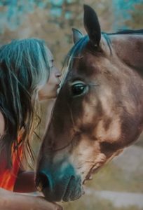 A woman kissing her horse's forehead.