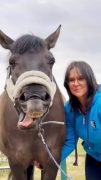 A woman smiling, with a yawning horse!