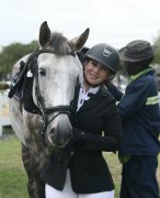 A woman standing with her horse, smiling.