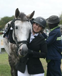 A woman standing with her horse, smiling.