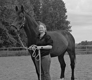 A woman standing with her horse.