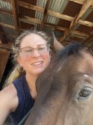 A woman smiling with her horse.