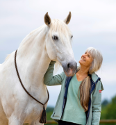 A woman smiling at her horse.