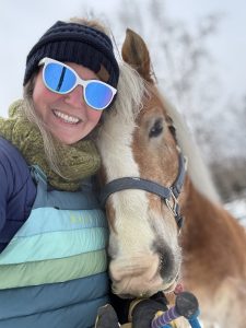 A woman standing with her horse.