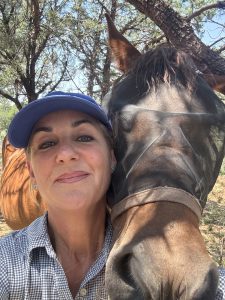 A woman smiling with her horse.