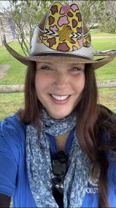 A woman smiling, wearing a great cowboy hat.