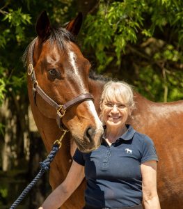 A woman standing with her horse.